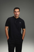 Rflx Reflection Polo in black, standing, hands at his sides, looking to camera