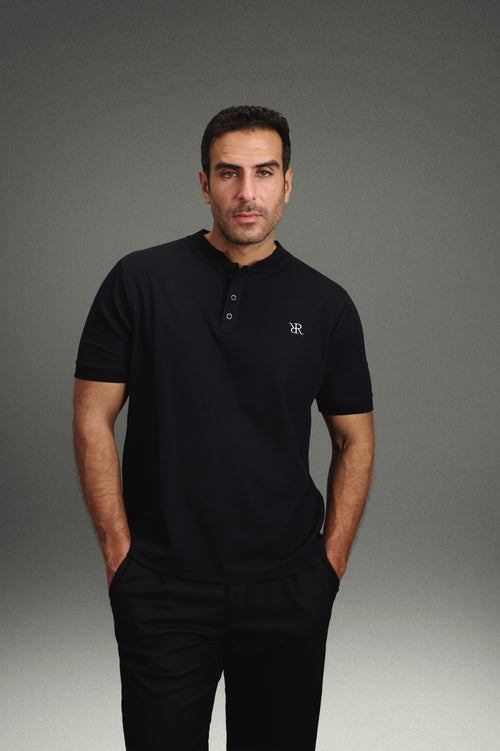 Rflx Reflection Polo in black, standing, hands at his sides, looking to camera