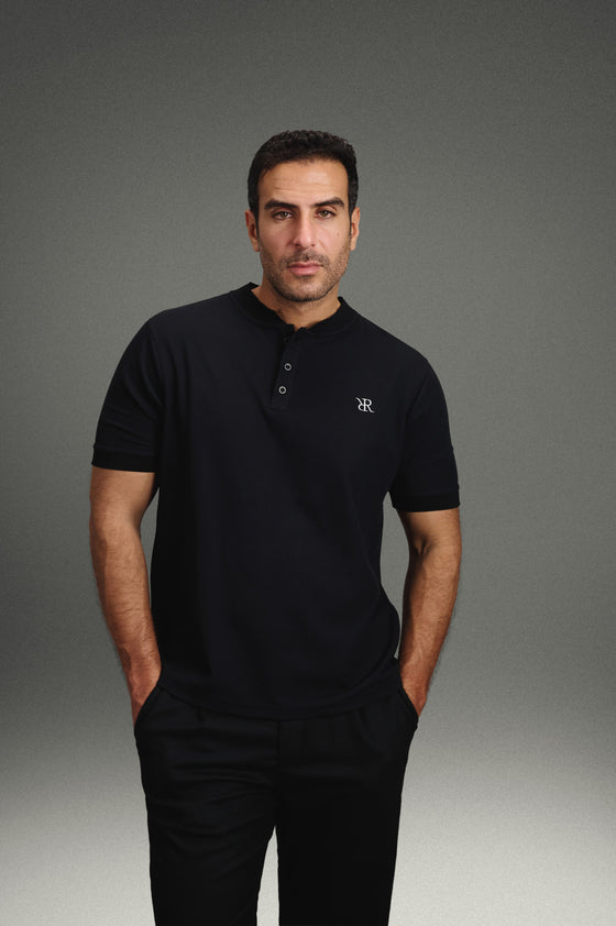 Rflx Reflection Polo in black, standing, hands at his sides, looking to camera