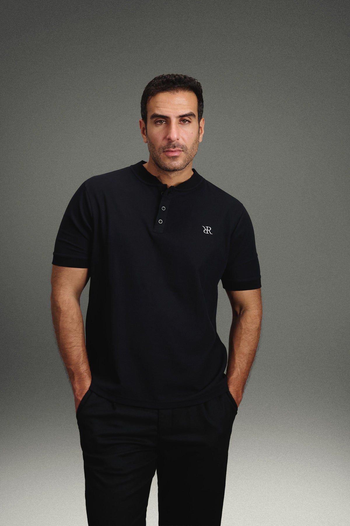 Rflx Reflection Polo in black, standing, hands at his sides, looking to camera