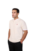Rflx Reflection Polo, a cotton knit polo with a ribbed mandarin band collar, in cream with white ribbed trim, three-quarter view showing the shoulder and ribbed cuff